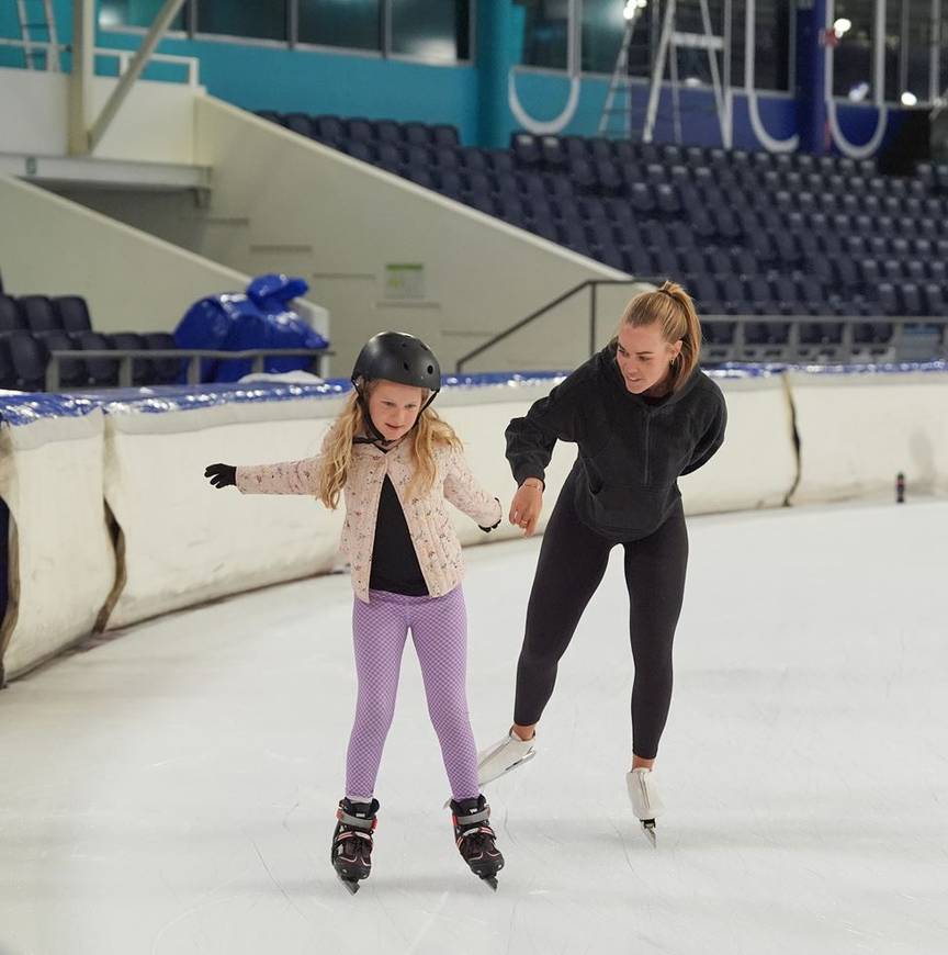 Martine Ripsrud helpt een meisje met schaatsen